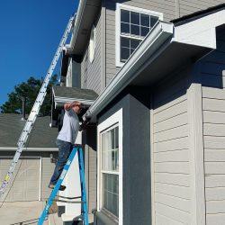 man on ladder installing gutters